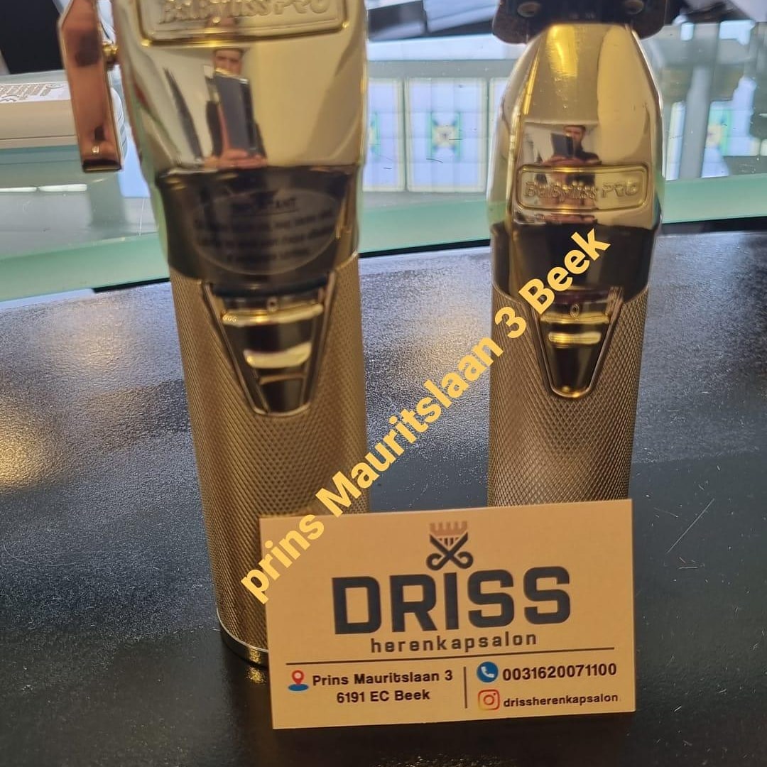 Twee gouden BaByliss PRO tondeuses naast het visitekaartje van de zaak