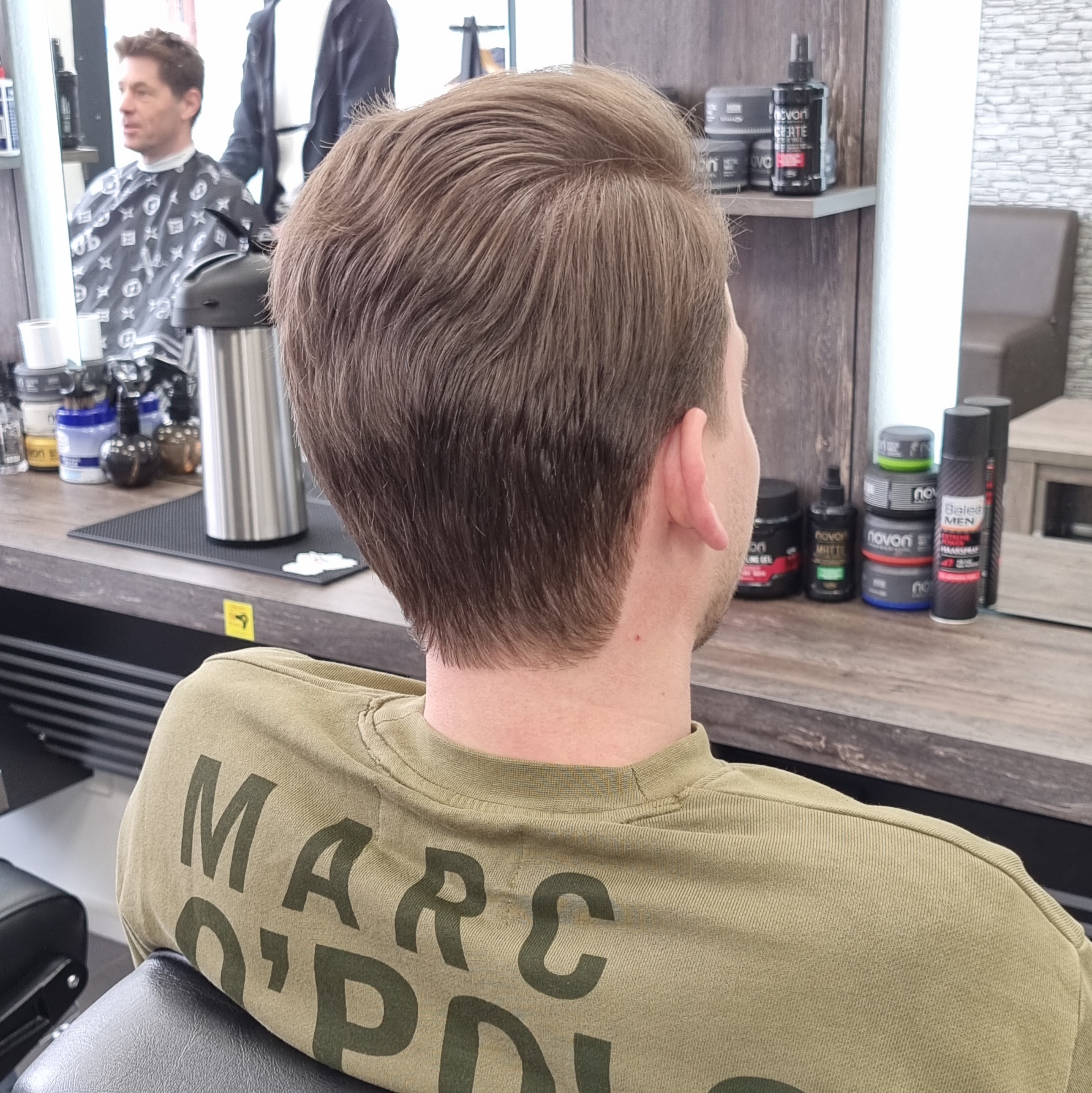 Een afgewerkt kapsel, strak opgeschoren in de nek met lengte bovenop