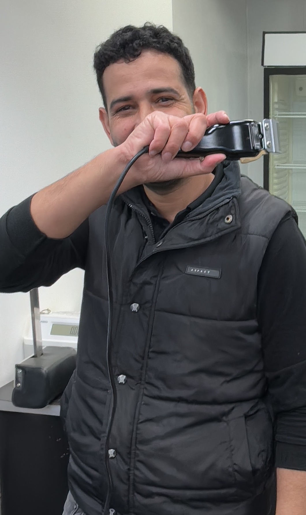 De kapper aan het werk in de salon, met zijn tondeuse in de hand
